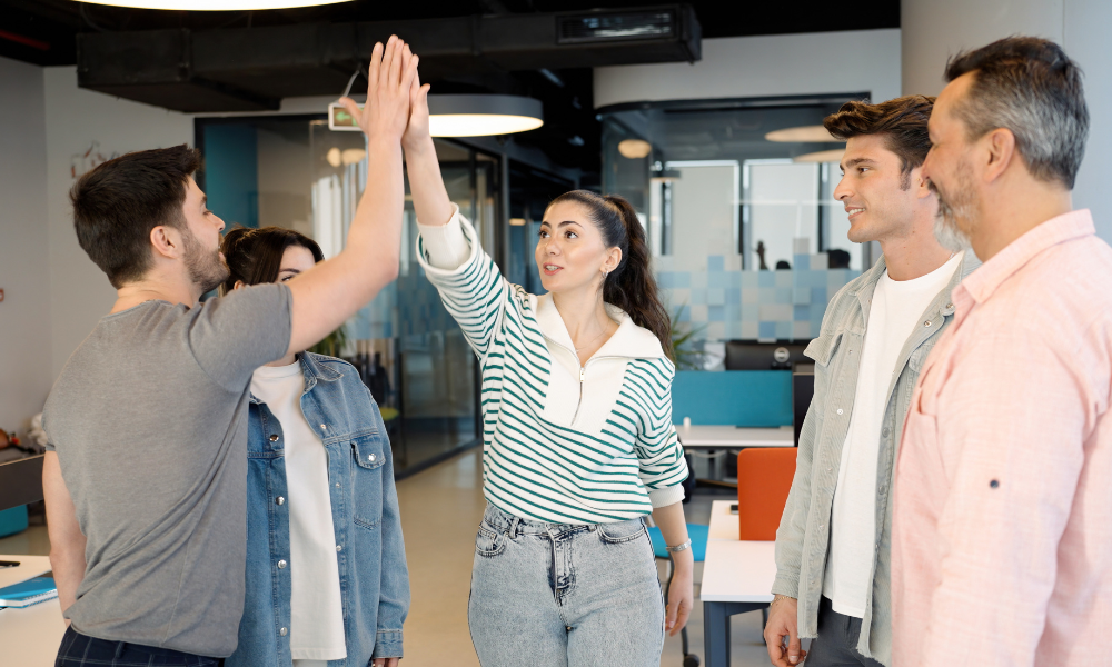 Young professionals celebrating teamwork with a high five in a modern office, reflecting collaboration with Best Payment Solutions